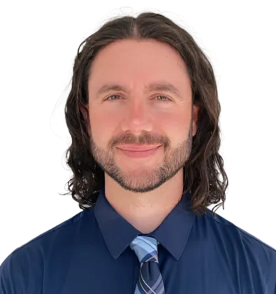 Smiling man with curly hair wearing a navy blue shirt and striped tie against a white background.