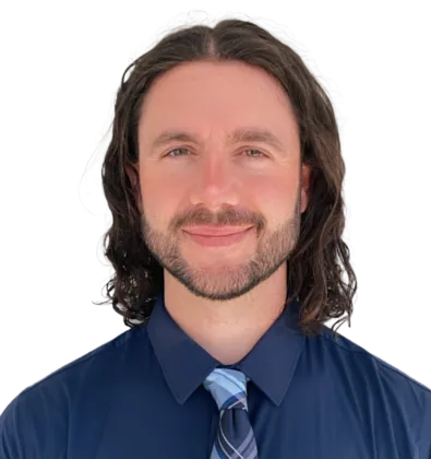 Smiling man with curly hair wearing a navy blue shirt and striped tie against a white background.