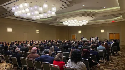 a group of people sitting in a room with a stage and a large group of people