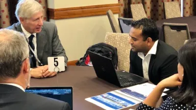 a group of people sitting at a table using a laptop
