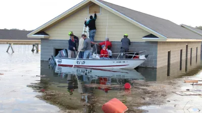 People on a boat accessing a flooded building's upper vent during severe flood conditions