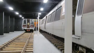 Two metro trains parked on parallel tracks inside an underground station with bright overhead lighting
