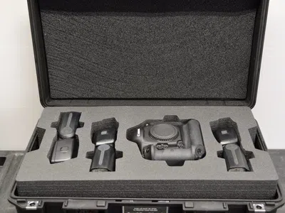 Black protective case with foam insert holding a camera body and accessories for secure transport.