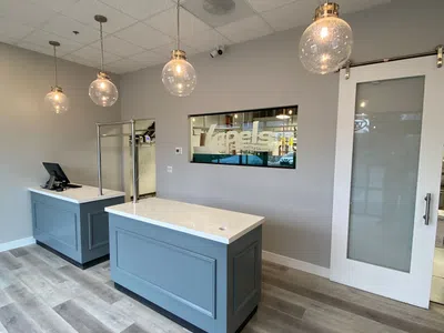 Modern reception area with blue counters, pendant lights, glass door, and light wooden flooring in a clean office space.