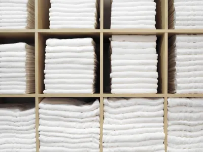 Neatly folded white towels stacked in wooden cubby shelves creating an organized storage display.