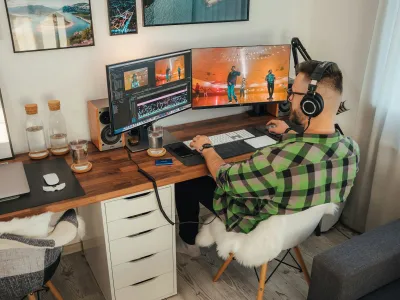 a person sitting at a desk with a computer and headphones on