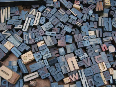 Assorted vintage wooden letterpress blocks scattered on a surface, showcasing various letters and numbers.