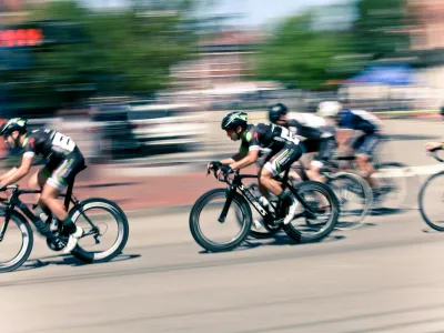 Cyclists in helmets racing at high speed in an outdoor urban road cycling competition