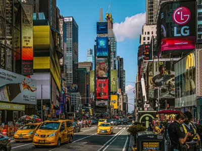 Busy New York City street with yellow taxis, skyscrapers, and vibrant digital billboards on a clear day