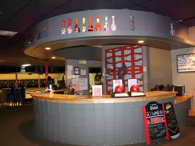Reception desk at bowling alley with colorful bowling pins decoration and seating area in background