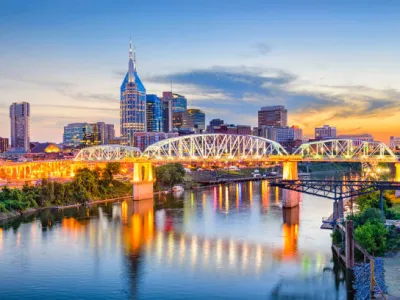 Nashville skyline at sunset with illuminated bridge reflecting on the Cumberland River