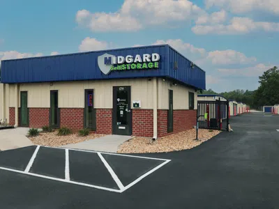 Midgard Self Storage facility with office building, gated units, and clear sky overhead on a sunny day