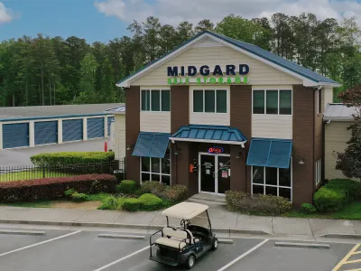 Midgard Self Storage building with office, surrounding storage units, and golf cart in front under blue sky.