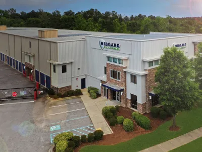 Modern Midgard Vacations headquarters with metal siding, brick accents, and landscaped greenery under sunlight.