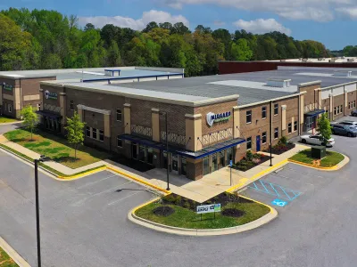 Aerial view of a modern commercial building with a landscaped parking area.
