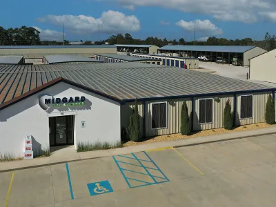 Midgard self storage facility with multiple storage units, office building, and handicap parking under a partly cloudy sky.