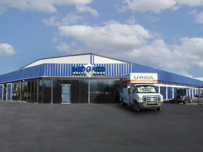 Midgard Self Storage building with a U-Haul truck parked outside under a blue sky with scattered clouds.