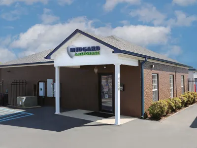 Small brick office building for Midgard Self Storage under sunny blue sky with white clouds