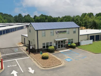 Midgard Self Storage facility with multiple storage units, office building, gated entrance, and accessible parking space.