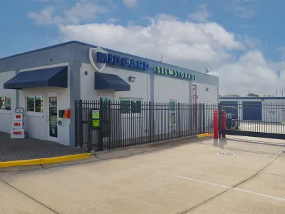 Midgard Self Storage facility with gated entrance and office building under a cloudy blue sky.