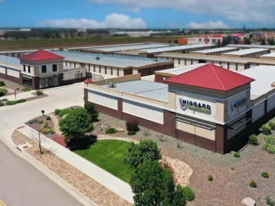 Aerial view of Midgard Self Storage facility with red-roofed buildings, green landscaping, and clear skies.