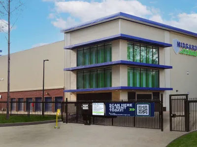 Modern Midgard Storage facility with secure gated entry and large glass windows during daytime.