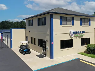 Two-story beige self storage office with blue trim and golf cart parked outside on a sunny day.