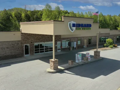 Exterior of Midgard Self Storage facility with stone facade and American flag on a sunny day