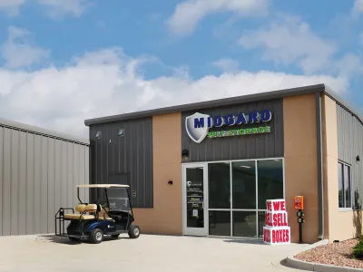 Midgard Self Storage building with golf cart parked outside and sign advertising boxes for sale.