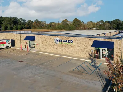 Aerial view of Midgard Self Storage building with U-Haul truck parked outside under blue sky.