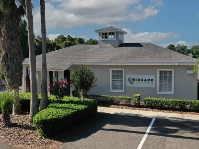 Midgard self-storage office building surrounded by palm trees and green shrubs under a blue sky.