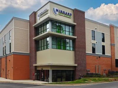 Modern Midgard Self Storage facility with brick and metal siding under a partly cloudy sky.
