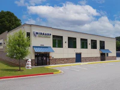 Modern Midgard Self Storage building with blue awnings, office entrance, and ample parking under a partly cloudy sky