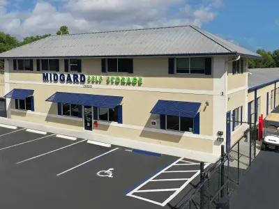 Exterior of Midgard Self Storage building with parking lot and handicap space on a sunny day.