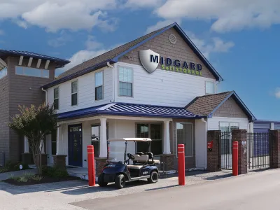 Modern self-storage facility with white building, blue metal roof, security gate, and golf cart parked outside