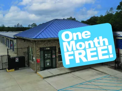 Storage facility building with blue roof and signage offering one month free rental promotion.