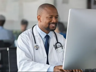a man smiling while using a laptop