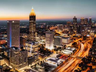 Aerial view of Atlanta’s skyline at sunset with vibrant city lights and bustling traffic.