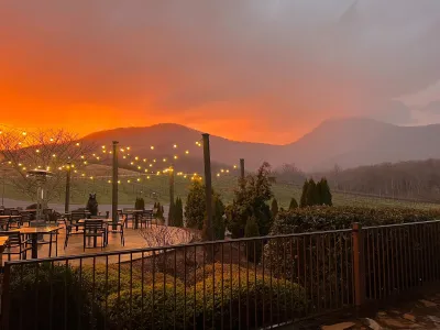 Outdoor patio with string lights at sunset overlooking vineyard and misty mountains in the background