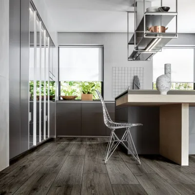 Modern kitchen with sleek cabinetry, wooden flooring, wireframe chair, island countertop, and hanging shelves with cookware.