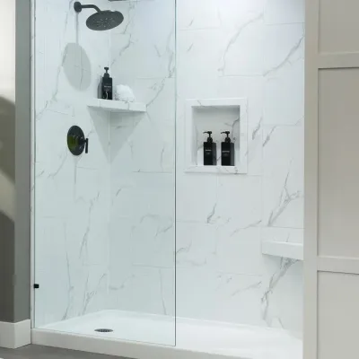 Modern walk-in shower with white marble tiles, black fixtures, built-in shelves, and glass door.