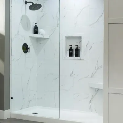 Modern bathroom shower with glass door, marble tile walls, black fixtures, and a tall potted plant beside it