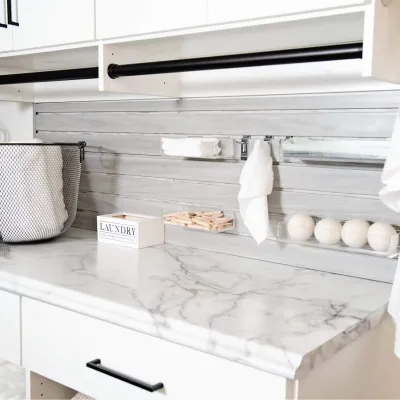 modern laundry room with marble countertop, hanging rod for clothing, mesh basket and laundry supplies