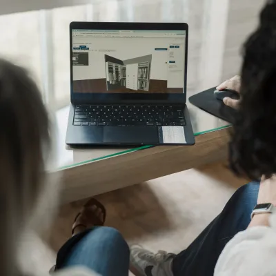 Closet designer with a 3D CAD design of a custom storage solution on a laptop screen with a new homeowner.
