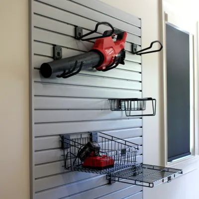 a leaf blower stored on slat wall in a garage