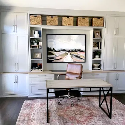 a room with white cabinets and a table with a chair and a shelf with baskets on it