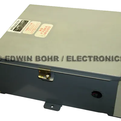 Gray metal electrical enclosure box with warning labels and latch on top, used for housing electronic components.
