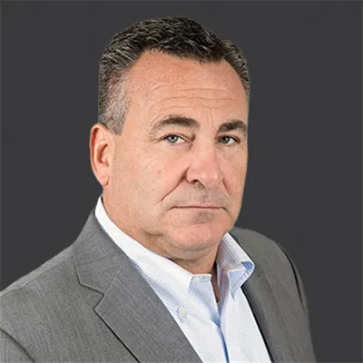 Middle-aged man in gray suit and white shirt with a neutral expression against dark background