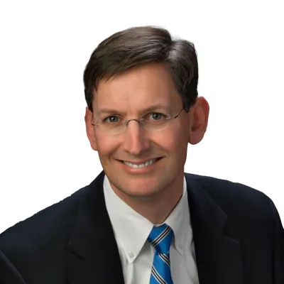 a man wearing a suit and tie smiling at the camera