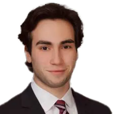 Professional headshot of a young man in a suit and tie with a neutral background.